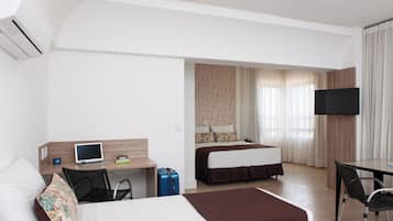 Habitación de hotel con cama, escritorio, silla y televisor.