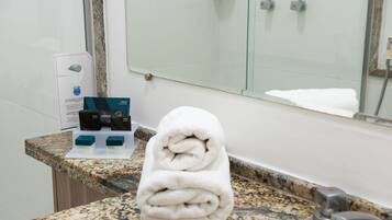 A bathroom with a granite countertop, a white towel, and soap dispensers.