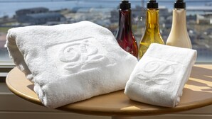 A bathroom with a window view of a cityscape, a wooden stool, and three bottles of toiletries. - Kushiro Prince Hotel (Kushiro)