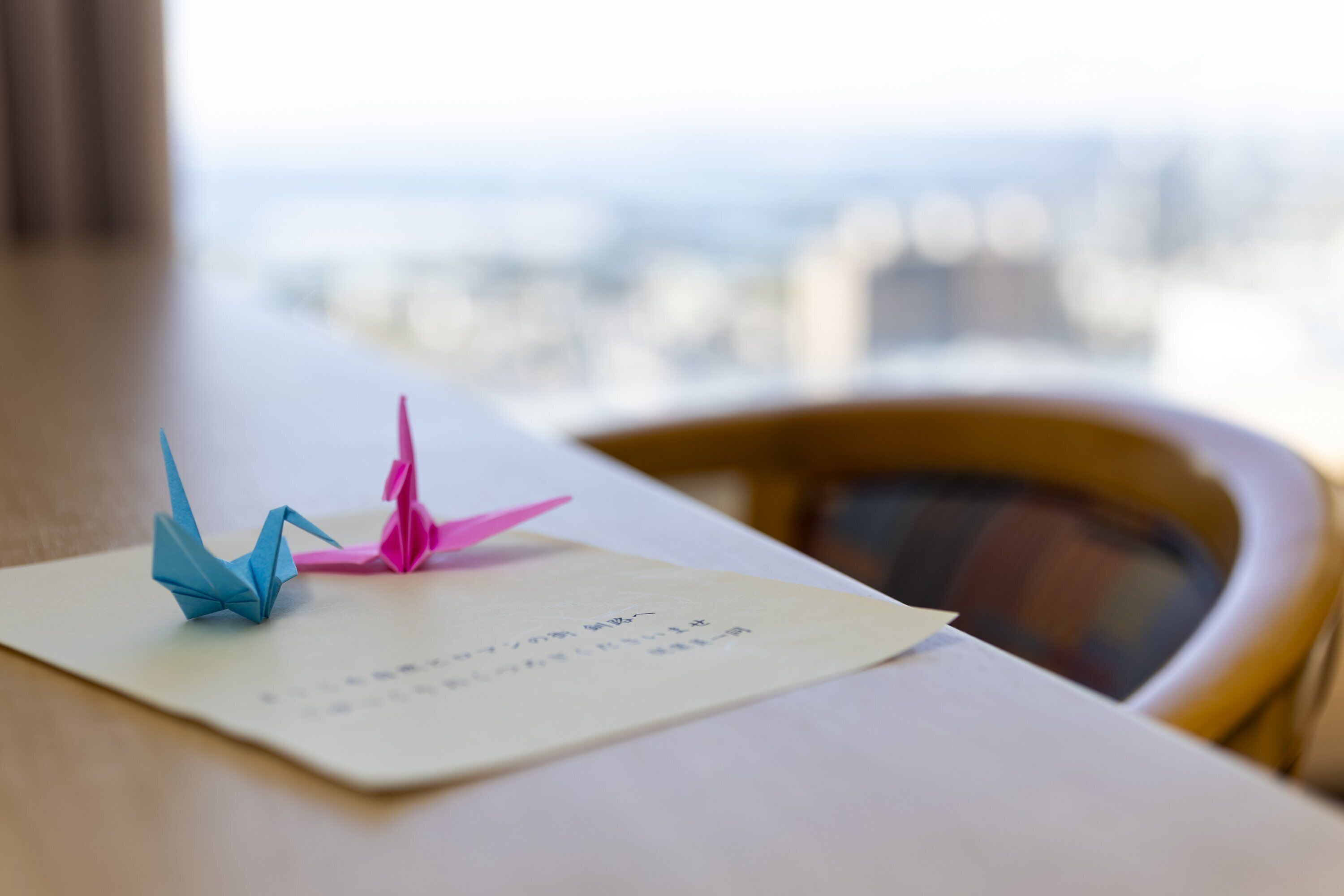 Una mesa con grullas de origami y un trozo de papel con texto manuscrito.