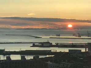 A coastal cityscape during sunset with buildings and boats. - Kushiro Prince Hotel (Kushiro)