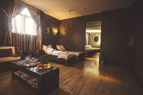 A spacious room with a large bed, a sofa, and a coffee table. There is a window with curtains, a wall-mounted light, and a mirror. - Canal Court Hotel (Newry)