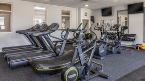 A gym with multiple treadmills, elliptical machines, and a wall-mounted TV. - Canal Court Hotel (Newry)