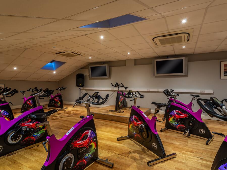 A fitness studio with stationary bikes, a TV, and a motivational poster on the wall.
