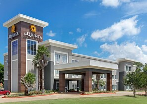Un hotel moderno con un llamativo letrero de 'La Quinta', un acceso cubierto y un césped bien cuidado.