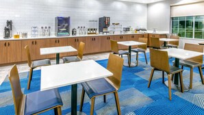 Un espace repas moderne, doté de tables et de chaises, d’une machine à café et d’un comptoir avec divers appareils.