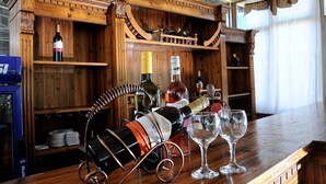 Een houten bar met wijnflessen en glazen.