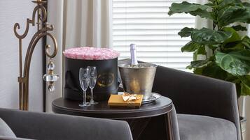 Una habitación con un sofá de color oscuro, una mesita auxiliar con un cubo para champán, copas y un objeto decorativo.