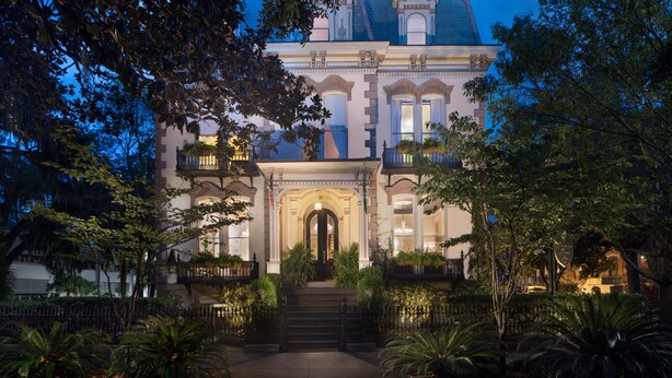 A grand, historic building with a symmetrical facade, large windows, and a central entrance with steps leading up to it.