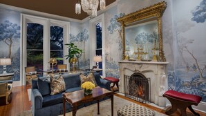 A living room with a fireplace, a blue sofa, a chandelier, and a large mirror.