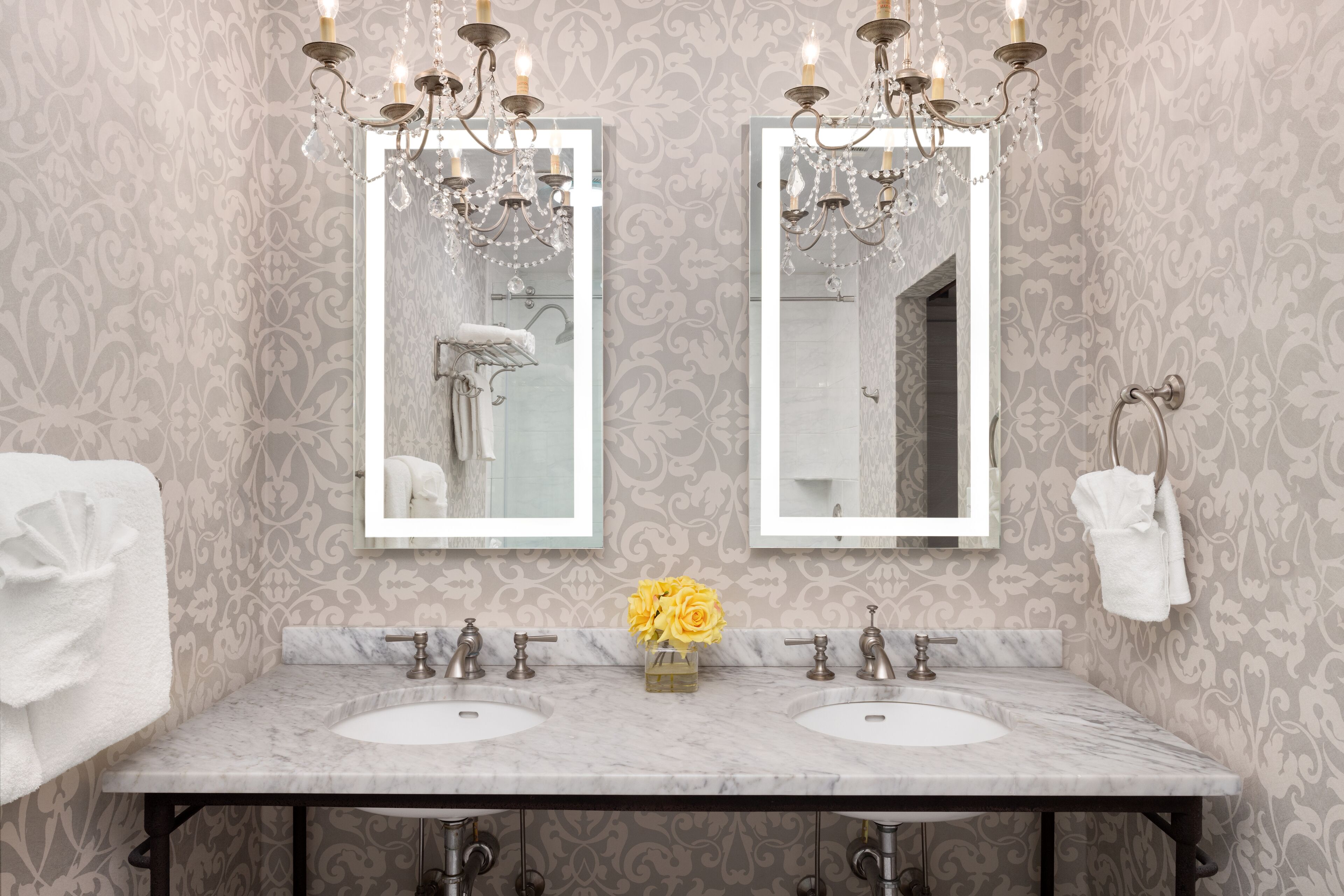 A bathroom with two sinks, a mirror, and a chandelier.