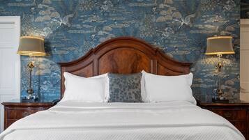 A neatly made bed with white linens, a wooden headboard, and two bedside lamps.