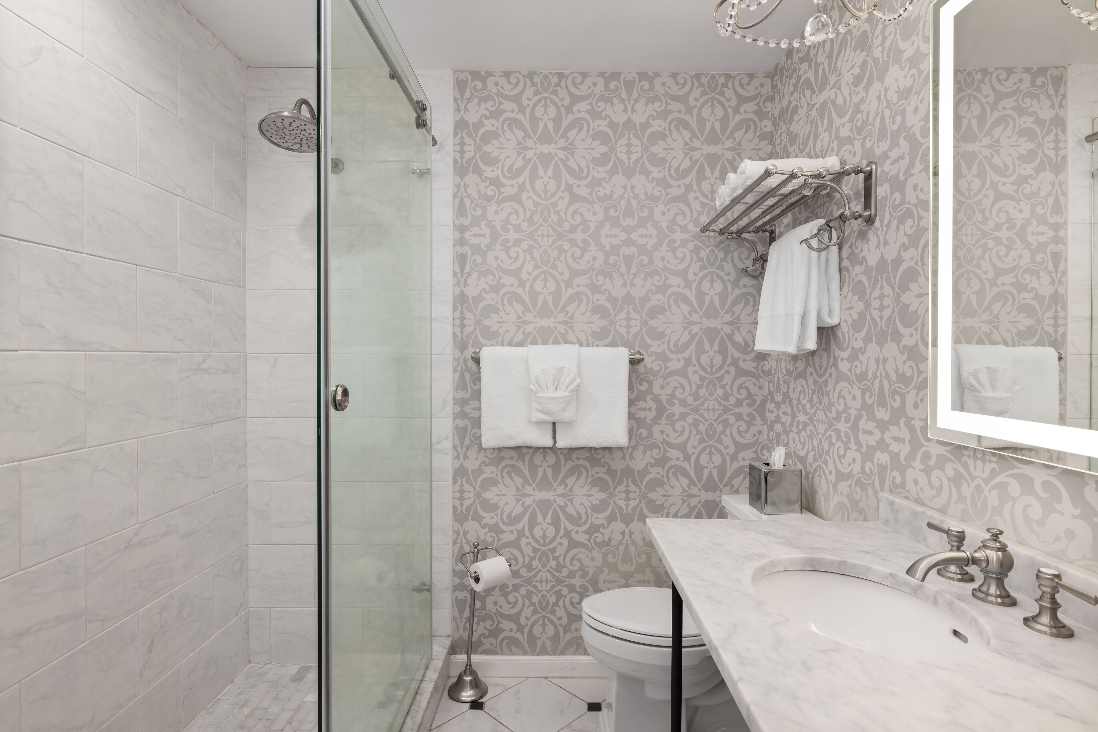A modern bathroom with a glass shower enclosure, a marble sink, and a toilet.