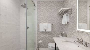 A modern bathroom with a glass shower enclosure, a marble sink, and a toilet.