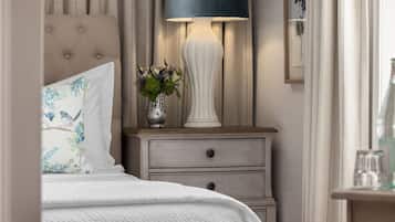 A bedroom with a bed, a nightstand with a lamp, and a vase with flowers.