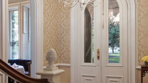A grand entrance with a wooden staircase, a chandelier, and a patterned rug.