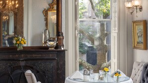 A dining room with a fireplace, a large mirror, and a view of the outdoors.