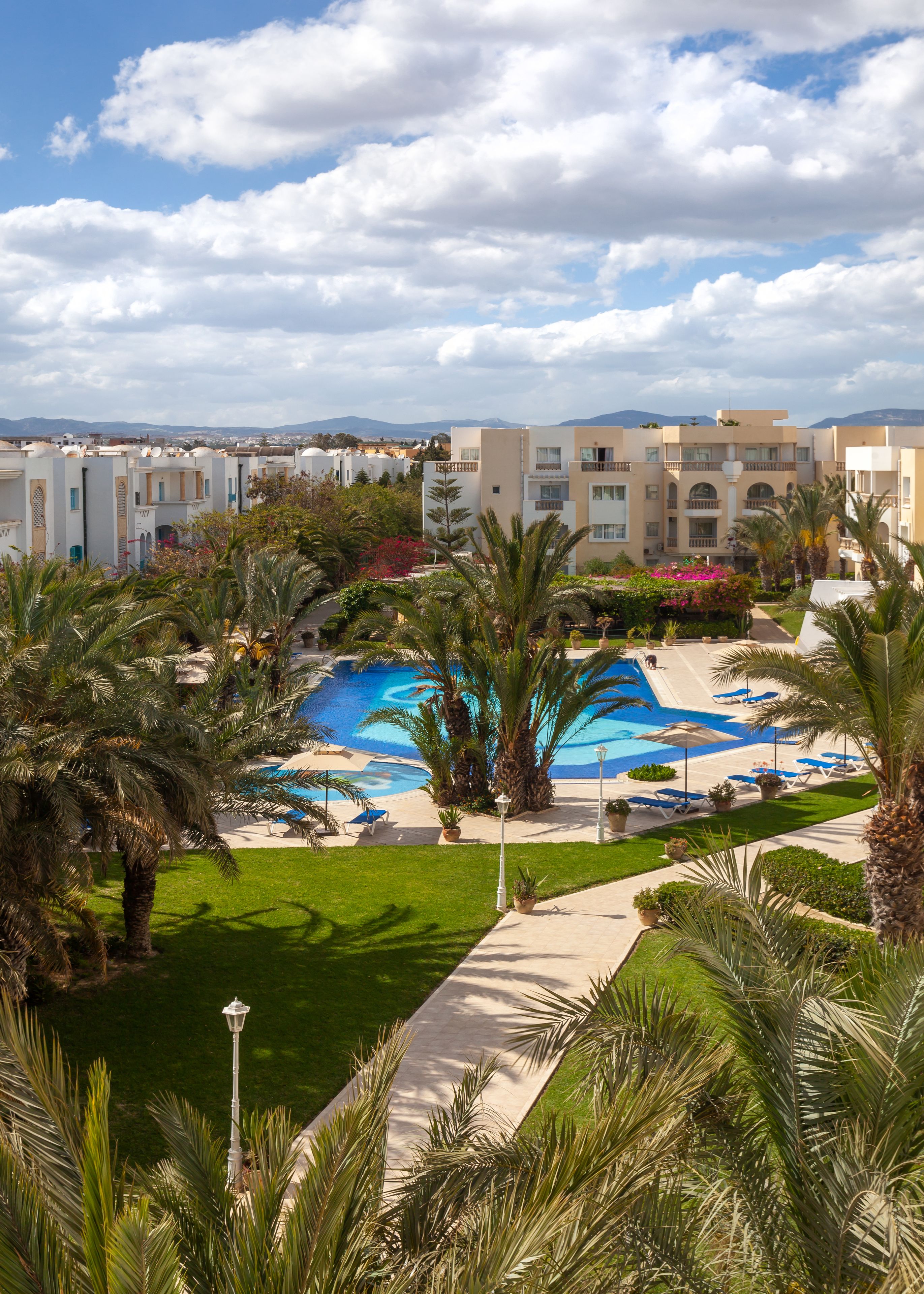 Ein Resort mit Swimmingpool, Palmen und Blick auf die Berge.