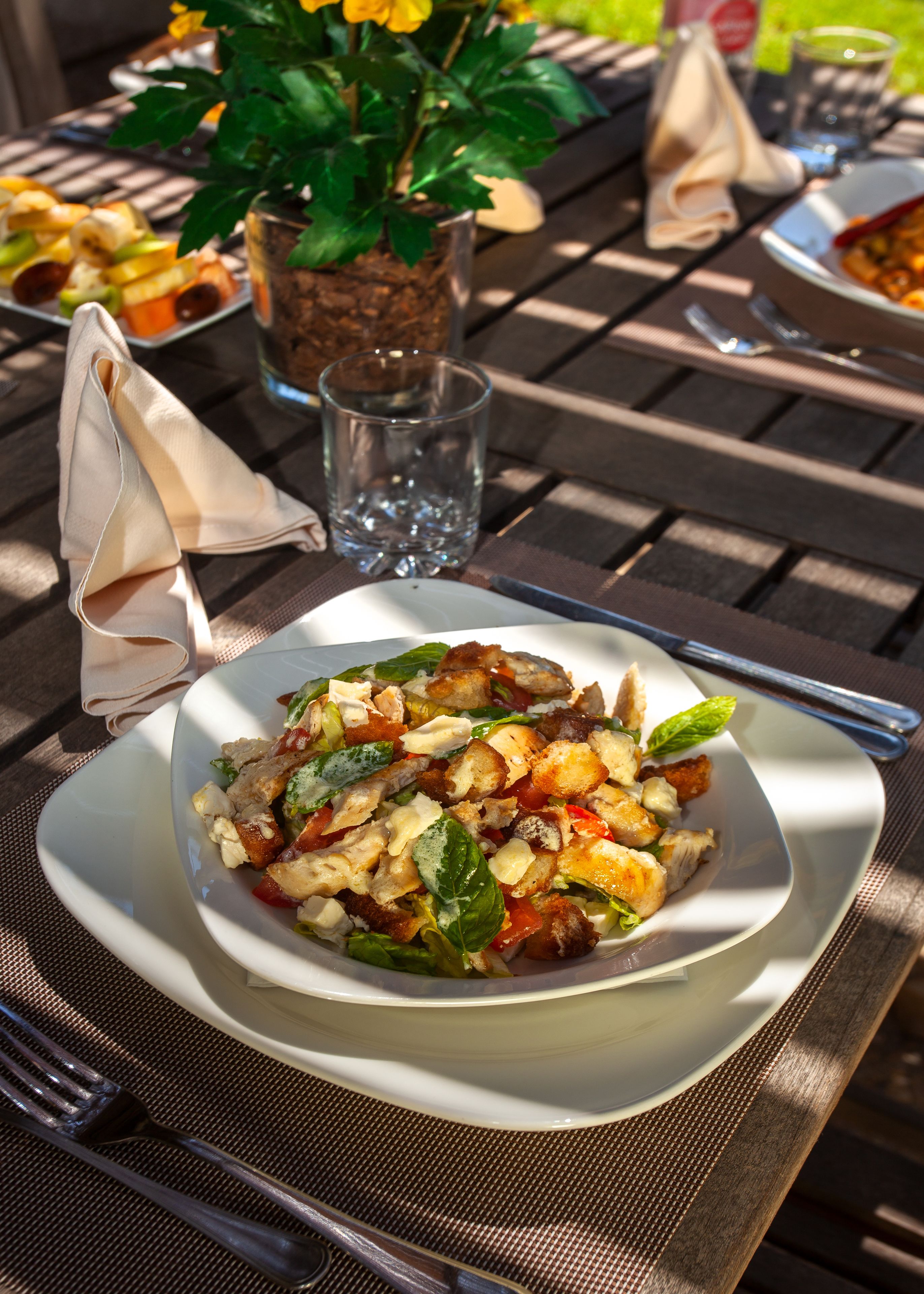 Une assiette blanche avec une salade, posée sur une table en bois.
