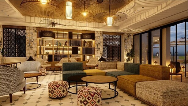 A modern lounge with sofas, armchairs, and ottomans, a patterned floor, and a large window with a view.