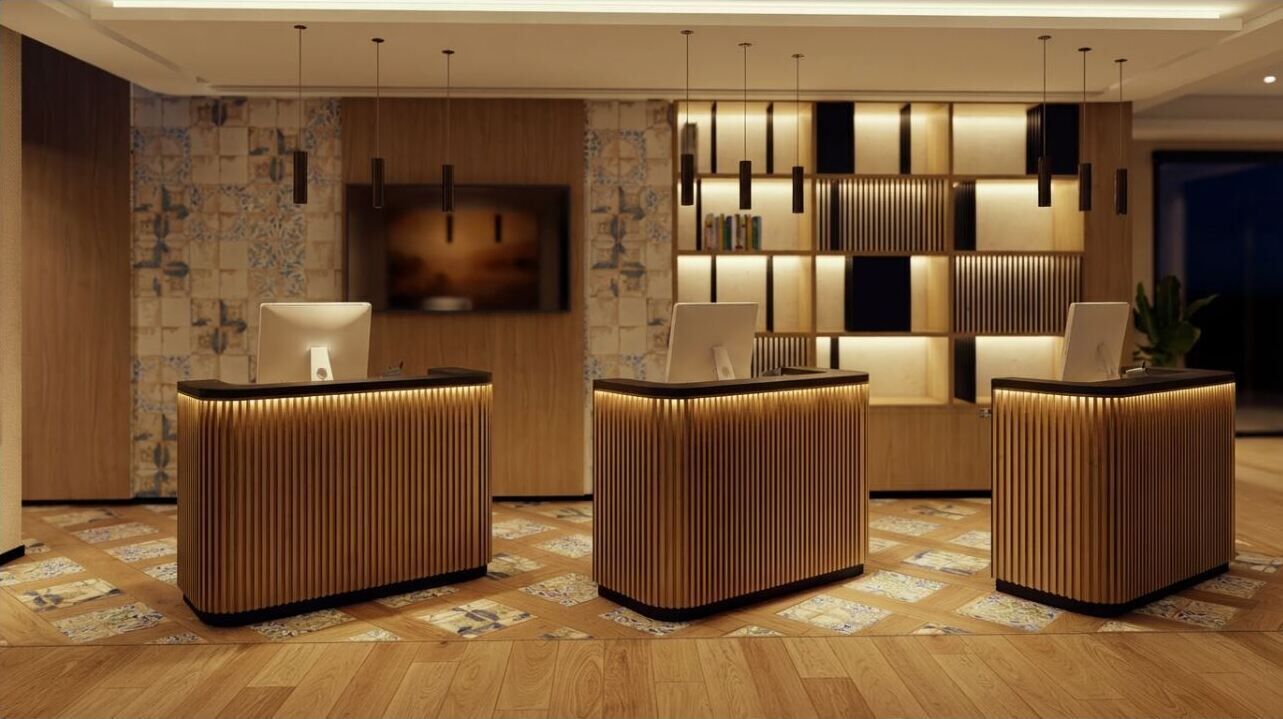 A reception area with three wooden reception desks, a wall-mounted TV, and a bookshelf with books.
