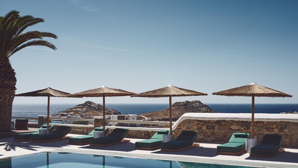 Un espace aménagé au bord de la piscine, avec des chaises longues et des parasols, offrant une vue sur le paysage côtier.
