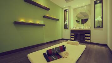 Um espaço de spa com mesa de massagem, prateleiras com velas, pia e espelho.