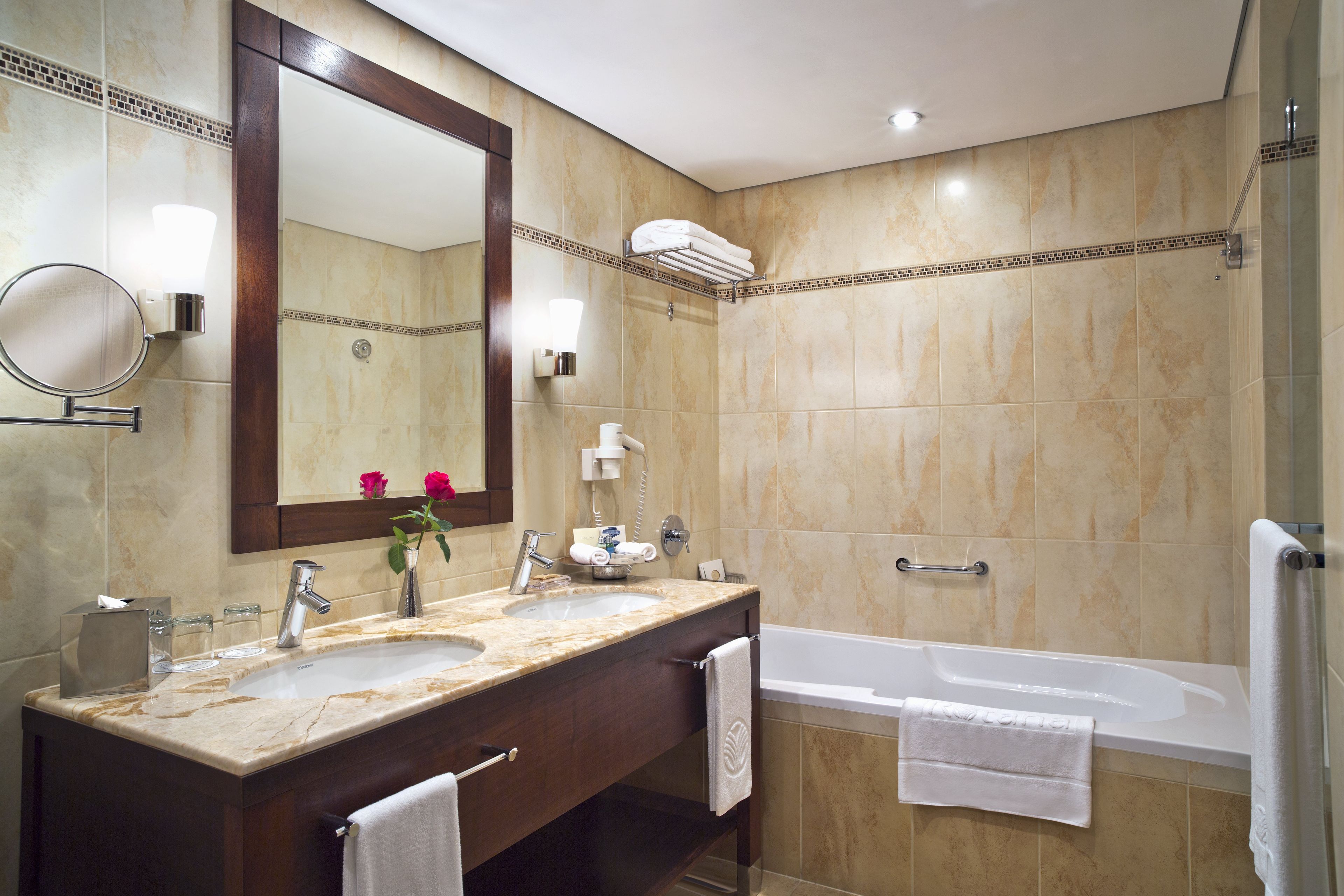 Un baño con tocador doble, un espejo grande, toallero, ducha y bañera.
