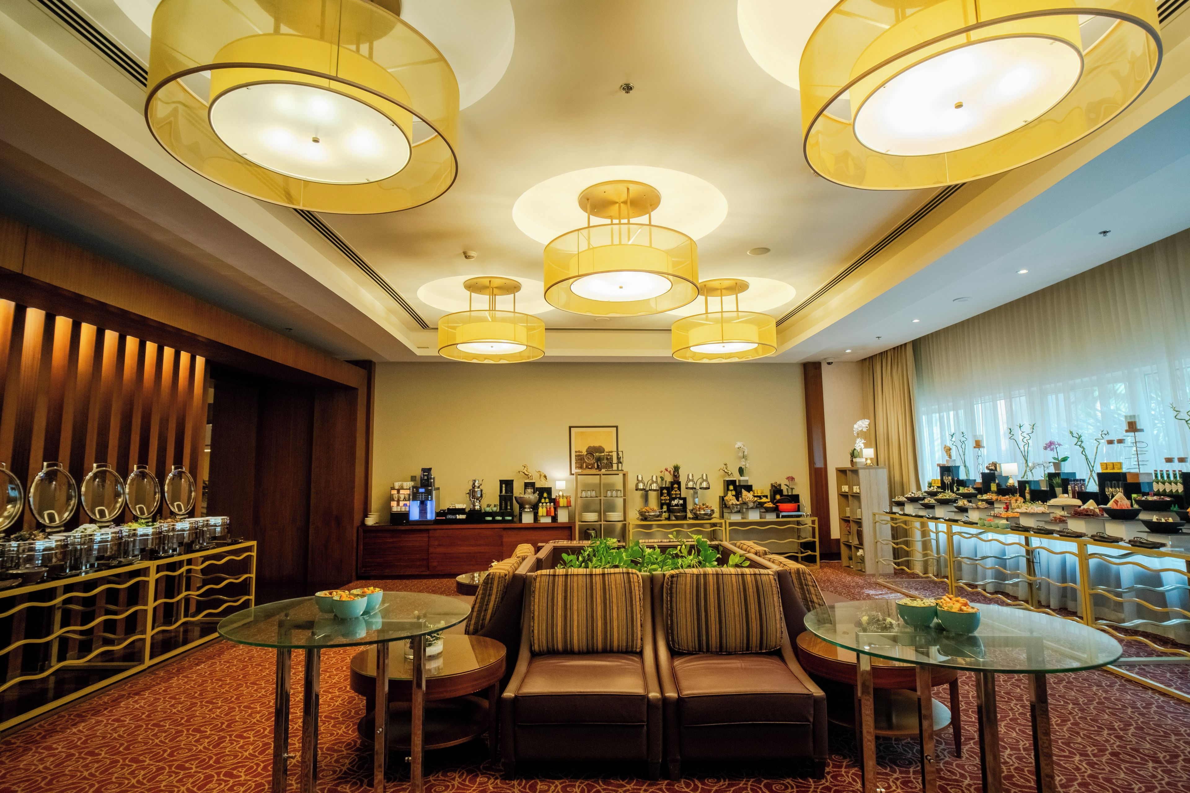 A hotel lobby with a seating area, a reception desk, and a buffet.