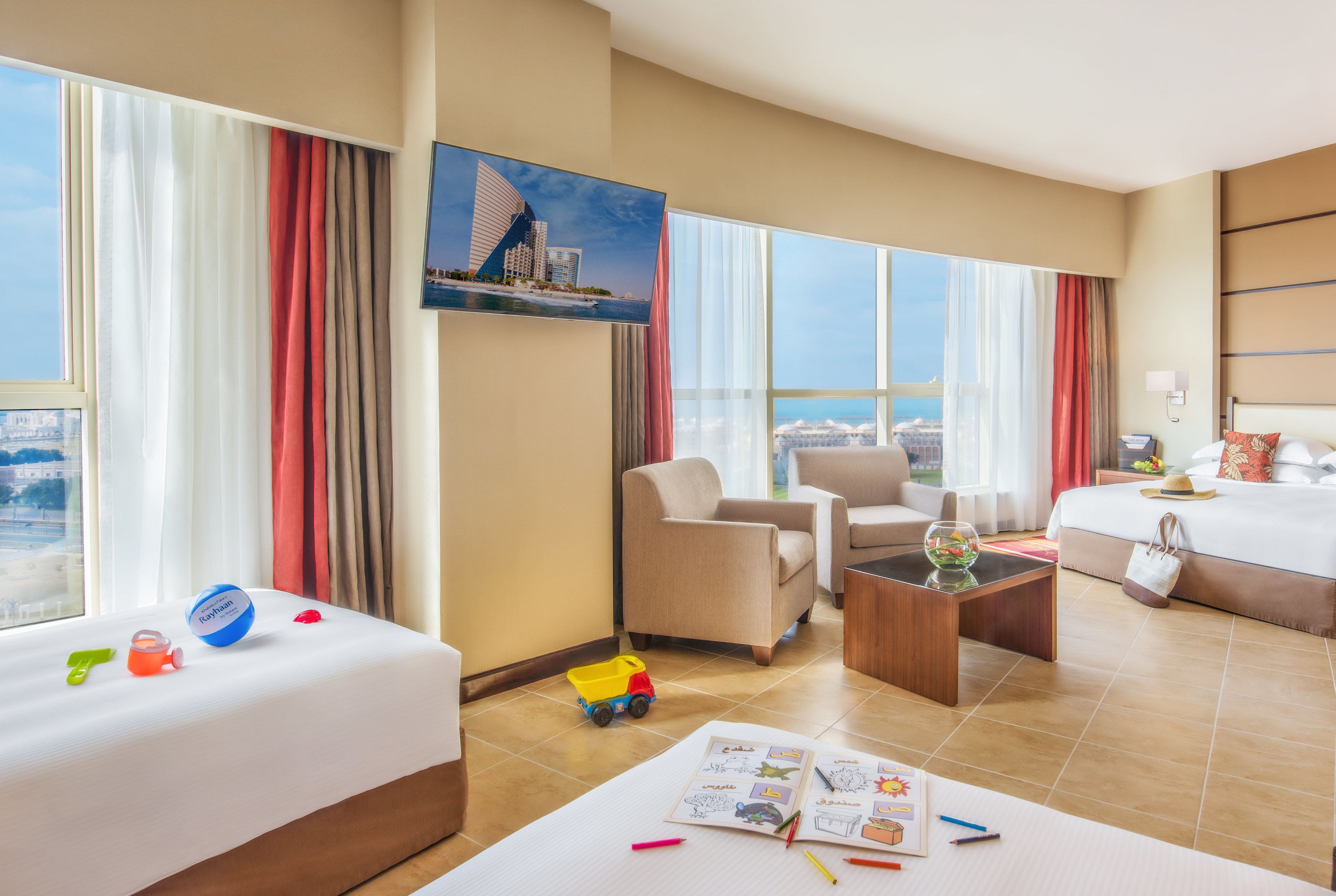 Habitación de hotel con cama, dos sillones, una mesa de centro y vistas a la ciudad.