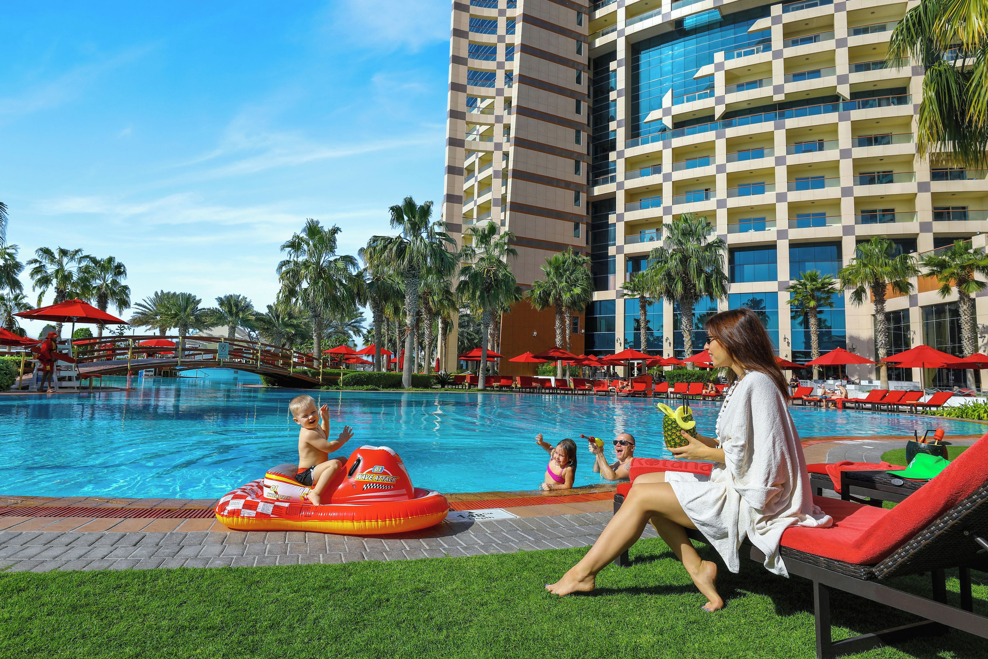 A poolside area with a water slide, lounge chairs, and a building with a checkered facade.