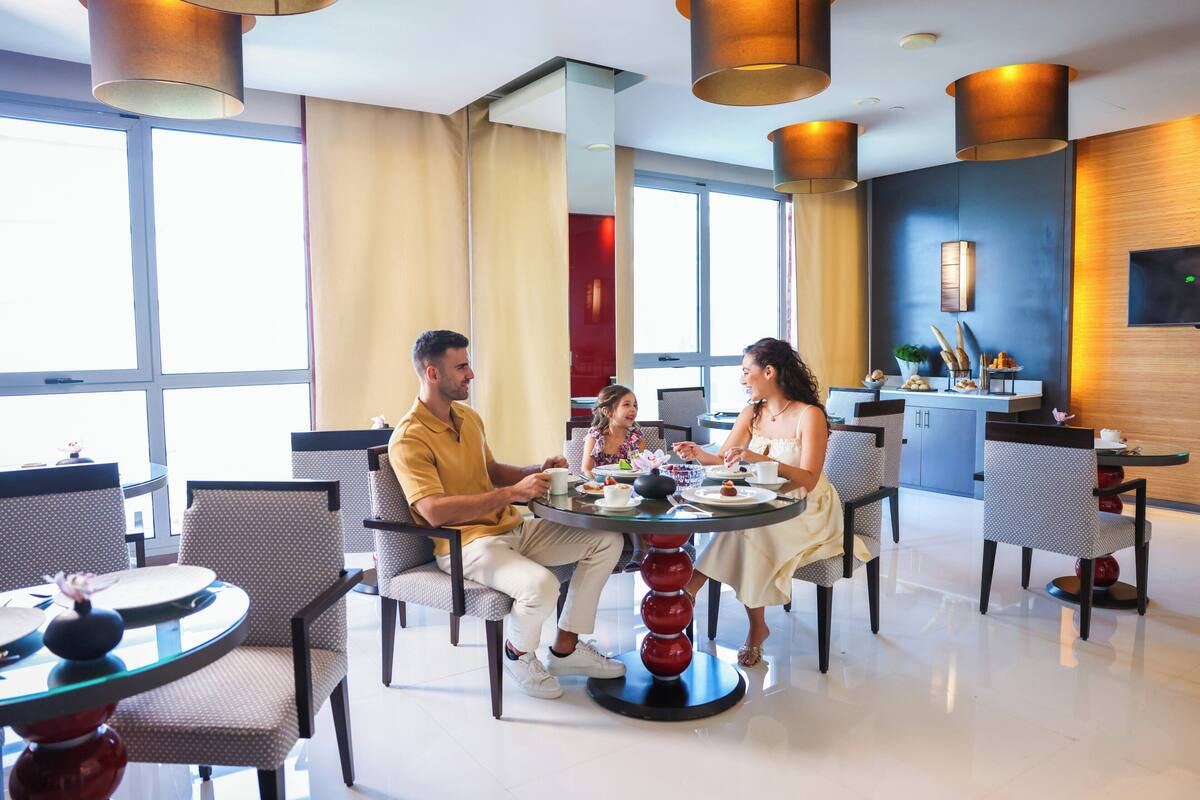 A hotel dining area with round tables, chairs, and a modern interior design.