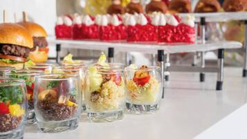 A variety of food items including sandwiches, desserts, and fruit-based drinks on a buffet table.