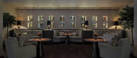 Un espace de détente moderne, doté de canapés, de fauteuils et de tables, et agrémenté d’œuvres d’art encadrées aux murs.