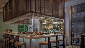 A bar area with a central island, bar stools, and a hanging chandelier. - Park Rotana (Abu Dhabi)