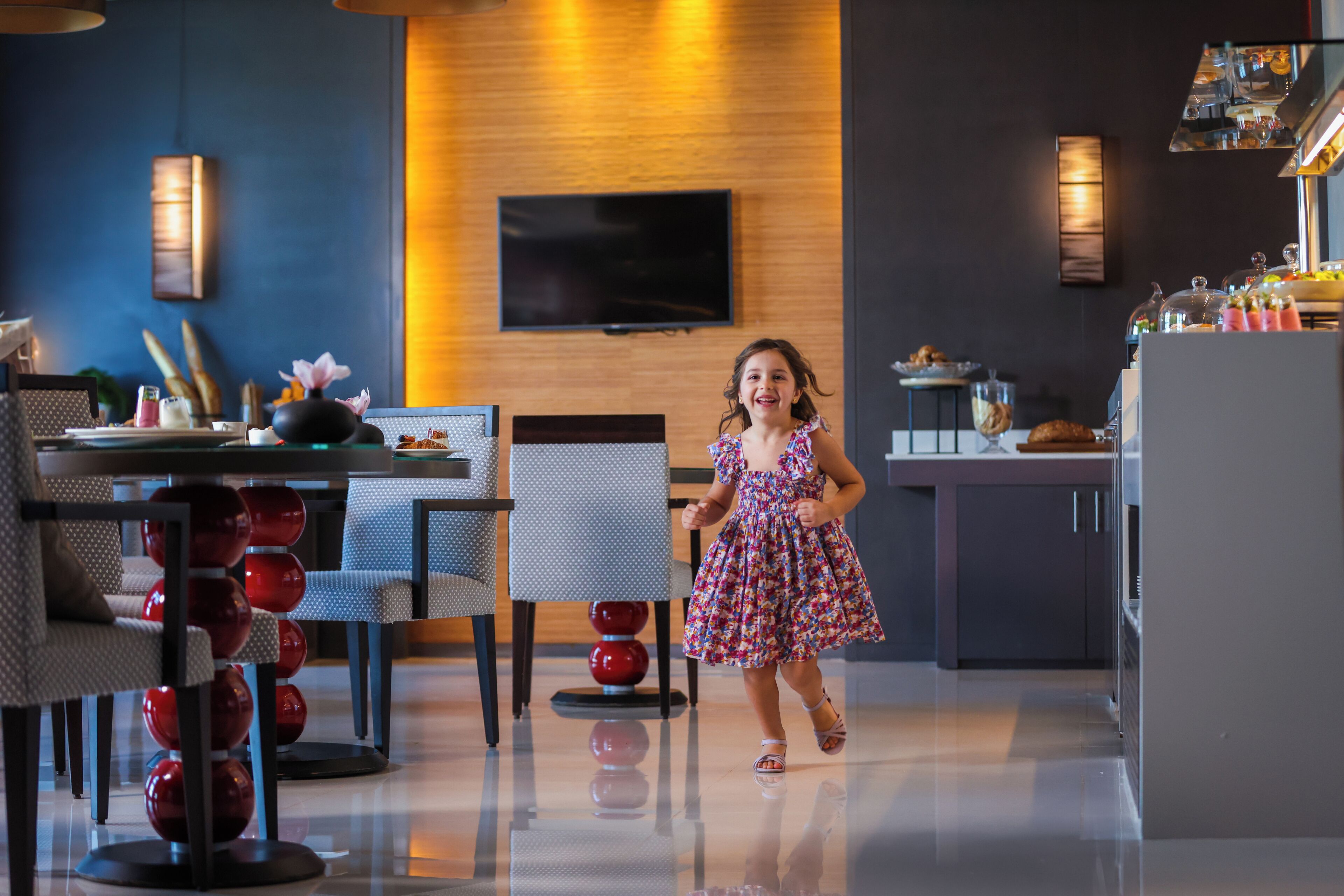 A modern interior with a dining area, kitchen, and a flat-screen TV mounted on the wall.