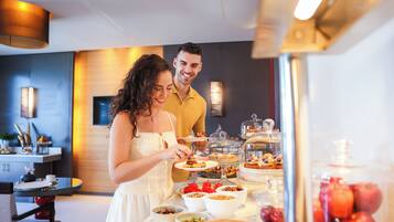Disposição de buffet com diversos alimentos e uma vitrine de vidro.