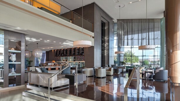 A spacious lobby with a high ceiling, modern furniture, and a bar area. - Park Rotana (Abu Dhabi)