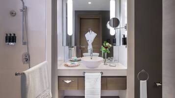 Un baño moderno con un espejo grande, un lavamanos blanco y una ducha.