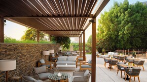 An outdoor patio with multiple seating areas, including sofas and chairs, arranged around tables and a central coffee table. - Park Rotana (Abu Dhabi)