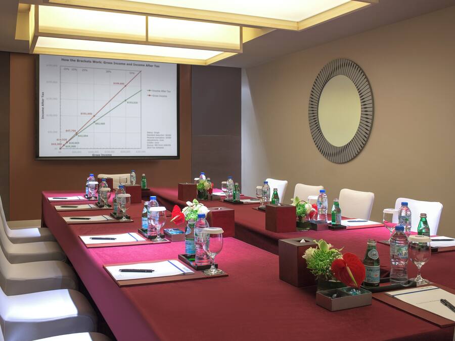 A conference room with a long table set for a meeting, equipped with water bottles, glasses, and notepads.