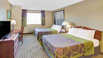 A hotel room with two beds, a TV, a desk, and a window with curtains.