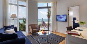 Una sala de estar moderna con sofá, sillón y mesa de centro. Un amplio ventanal ofrece vistas al océano.