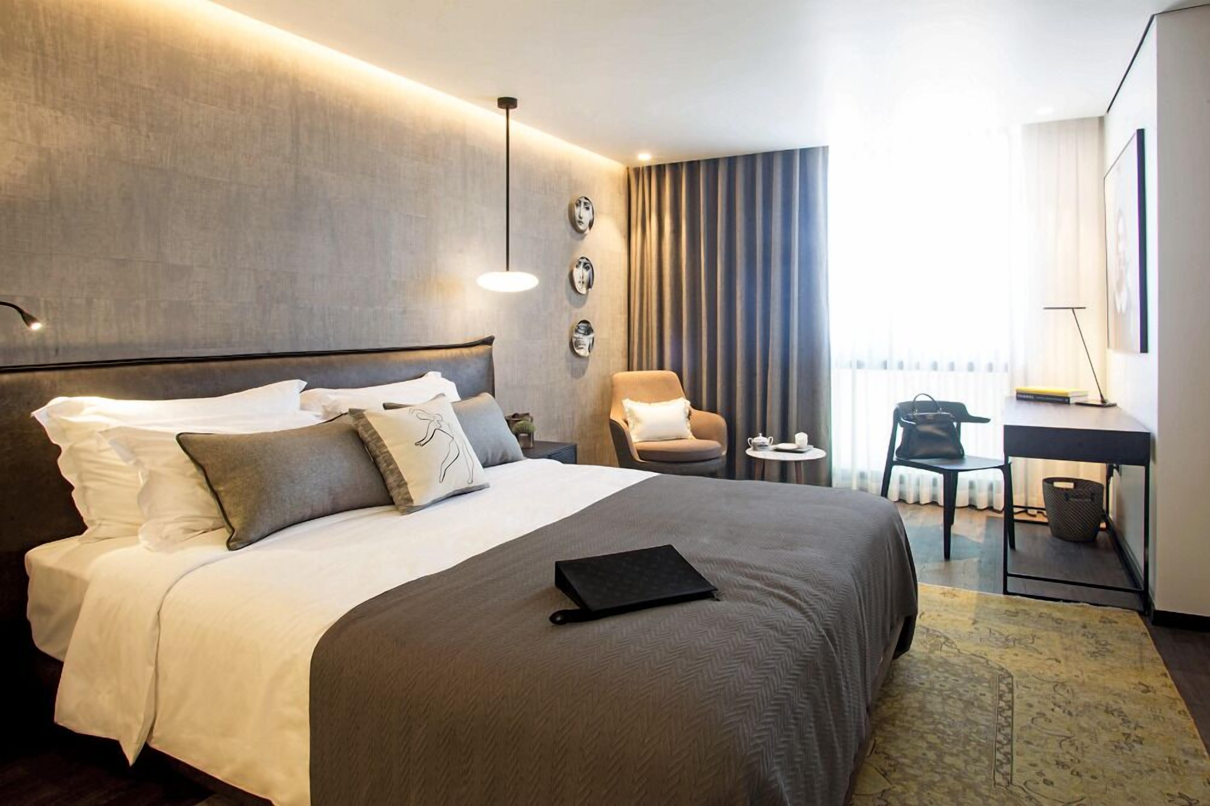 Ein Hotelzimmer mit einem großen Bett, einem Schreibtisch, einem Sessel und einem kleinen Tisch.
