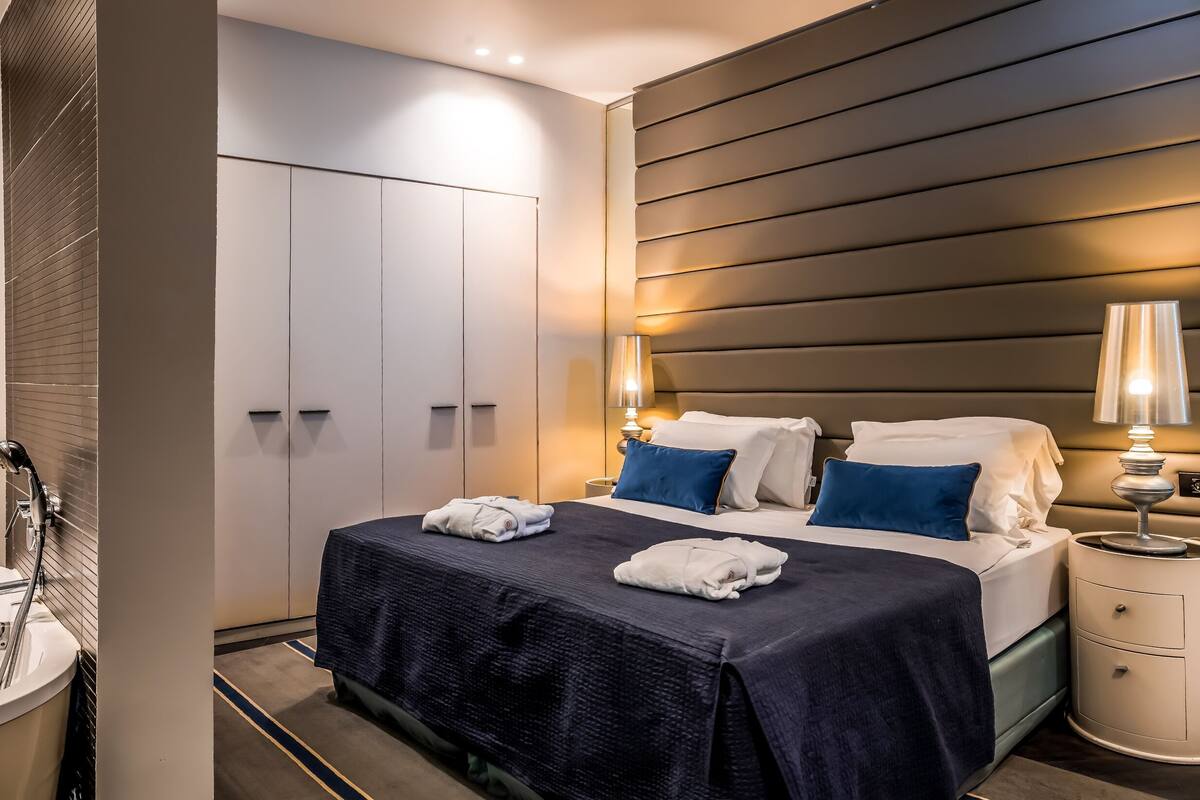 Habitación de hotel moderna con una cama grande, baño independiente y vestidor.