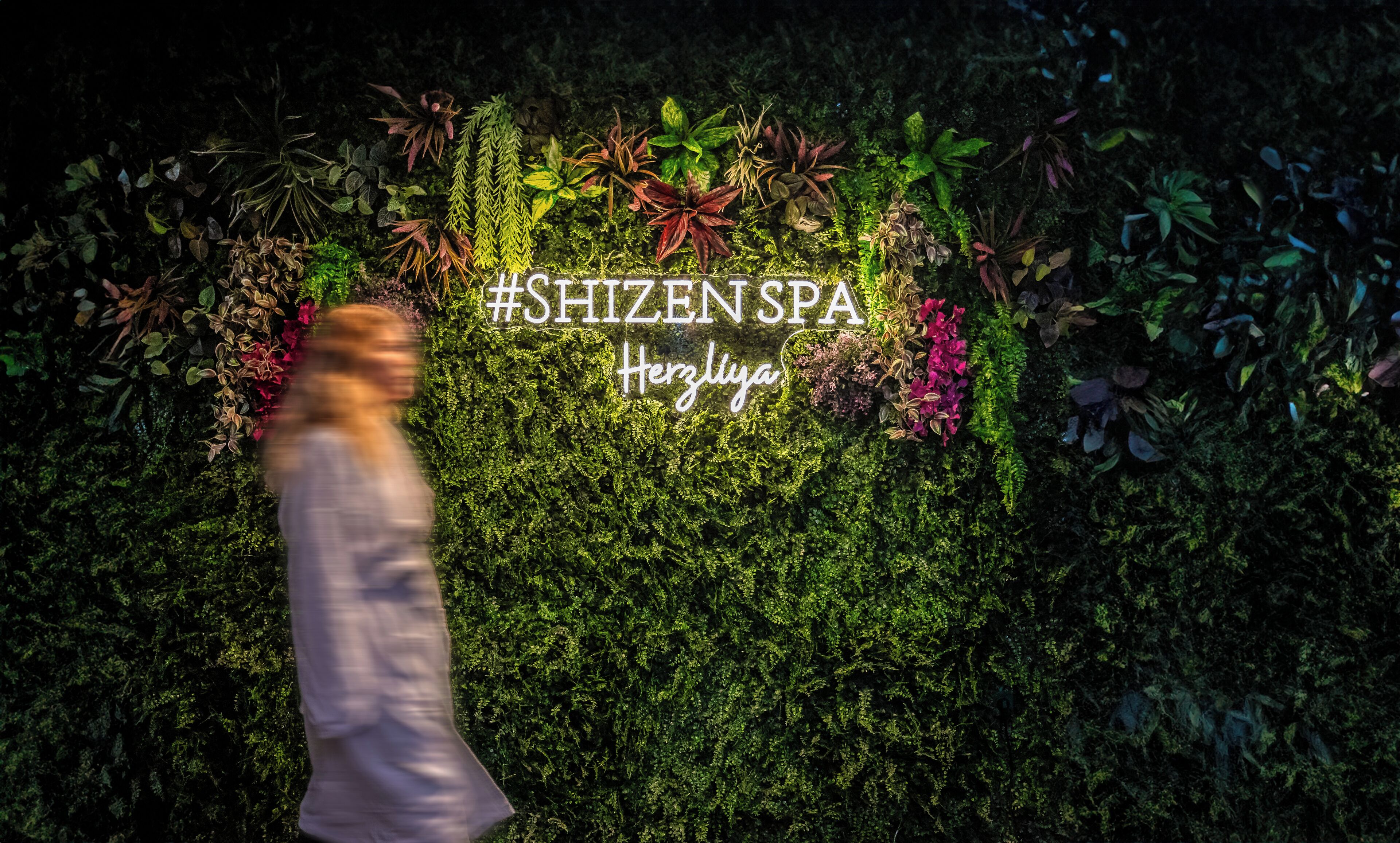 Una pared con un letrero #SHIZENSPA y la palabra "Herzliya" en el centro.