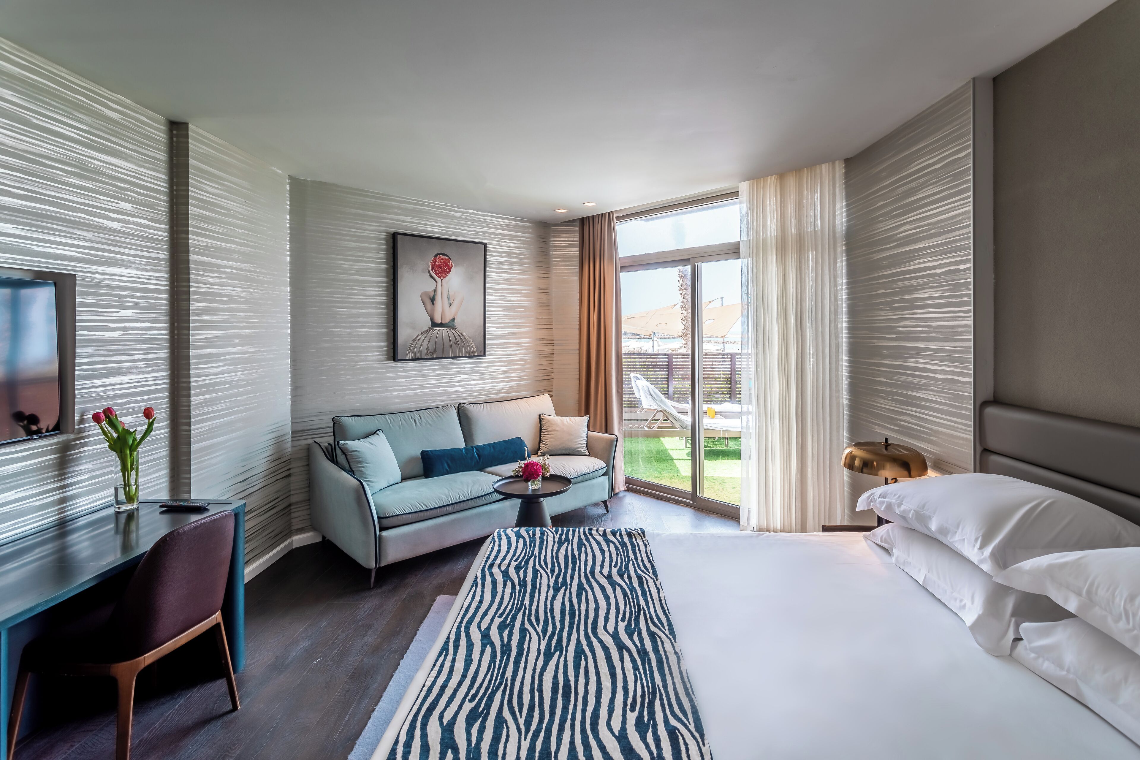 Una habitación de hotel moderna con cama, sofá, escritorio y televisión.