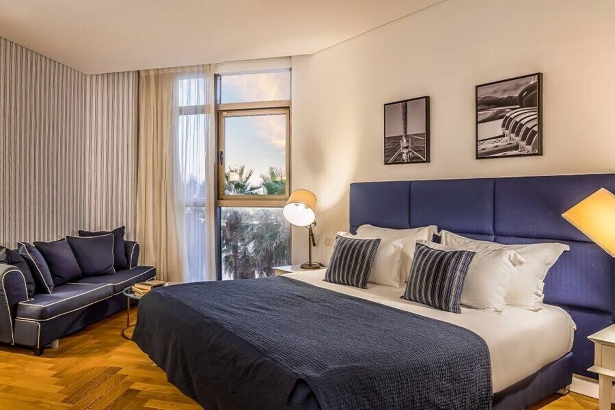 Una habitación de hotel con cama, sofá, escritorio y ventana con cortinas.