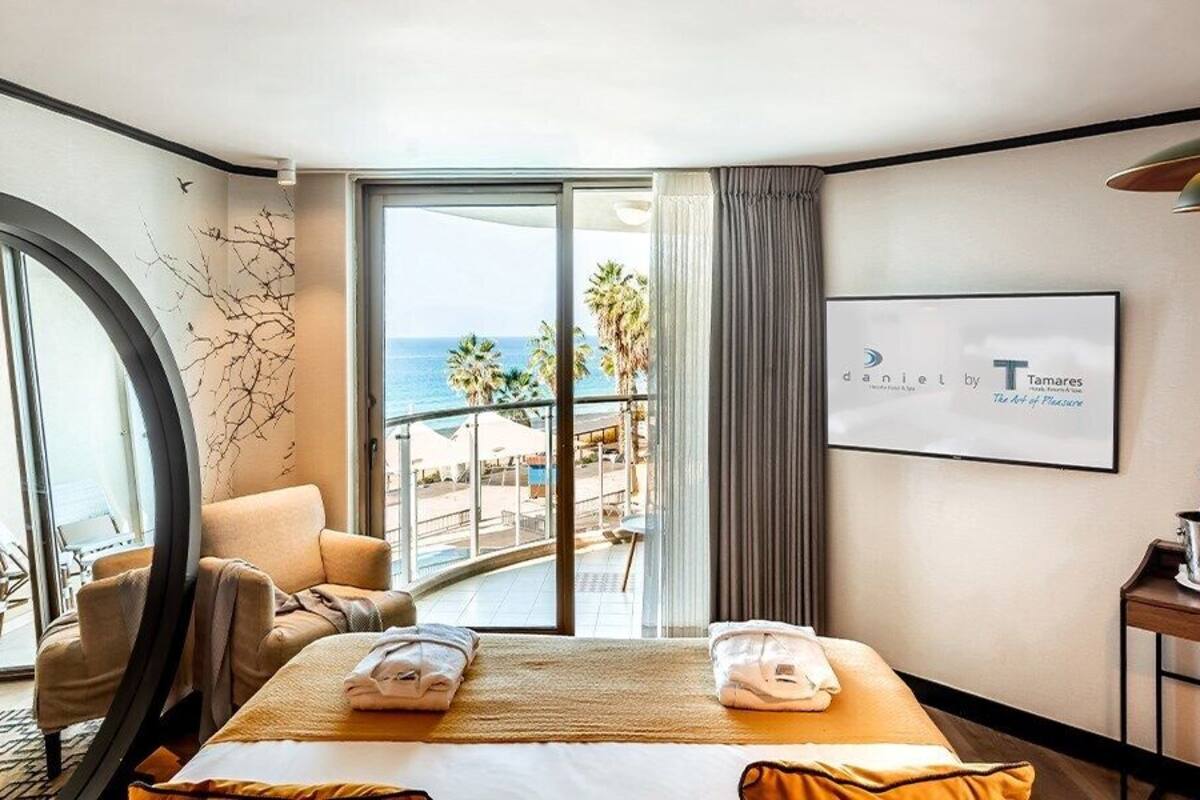 Una habitación de hotel con cama, una silla, una mesa y vista al océano.