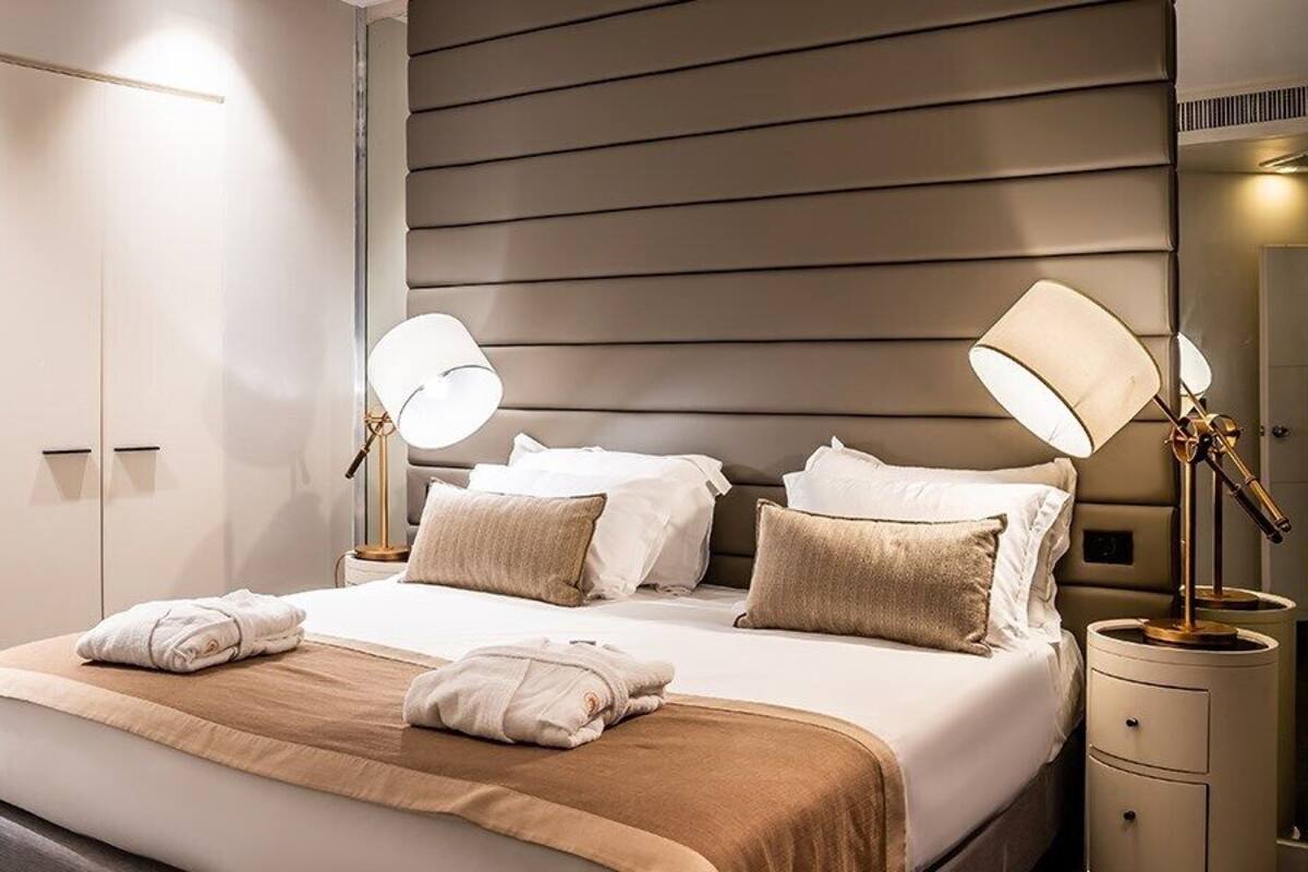 Una habitación de hotel moderna con una cama grande, dos lámparas de noche y un armario.